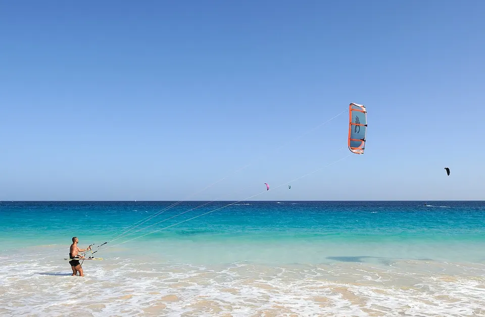 Kitesurfer auf dem Meer vor dem hellen Sandstrand der Kapverdeninsel Sal