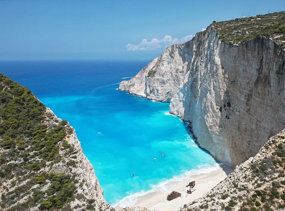 Die Navagio-Bucht auf Zakynthos mit dem Schiffswrack am hellen Strand und steilen Kalkfelsen
