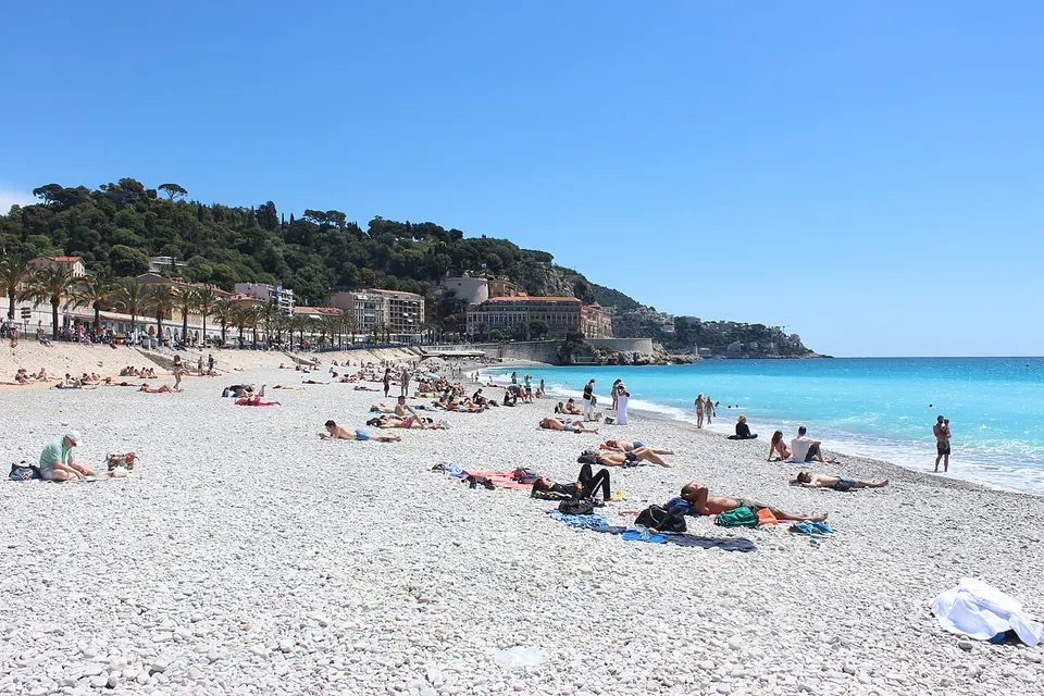 Der Kiesstrand an der Promenade des Anglais in Nizza mit blauem Meer