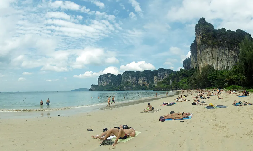 Longtailboote am Strand von Railay bei Krabi, mit hohen Kalksteinfelsen und türkisfarbenem Wasser