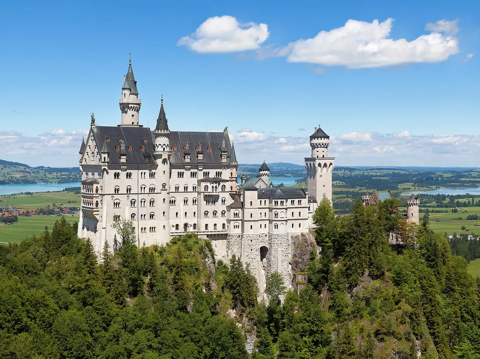 Schloss Neuschwanstein auf einem bewaldeten Felsen vor den Allgäuer Alpen