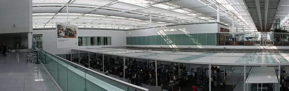 Sicherheitskontrolle am Flughafen München mit Scannern und wartenden Reisenden
